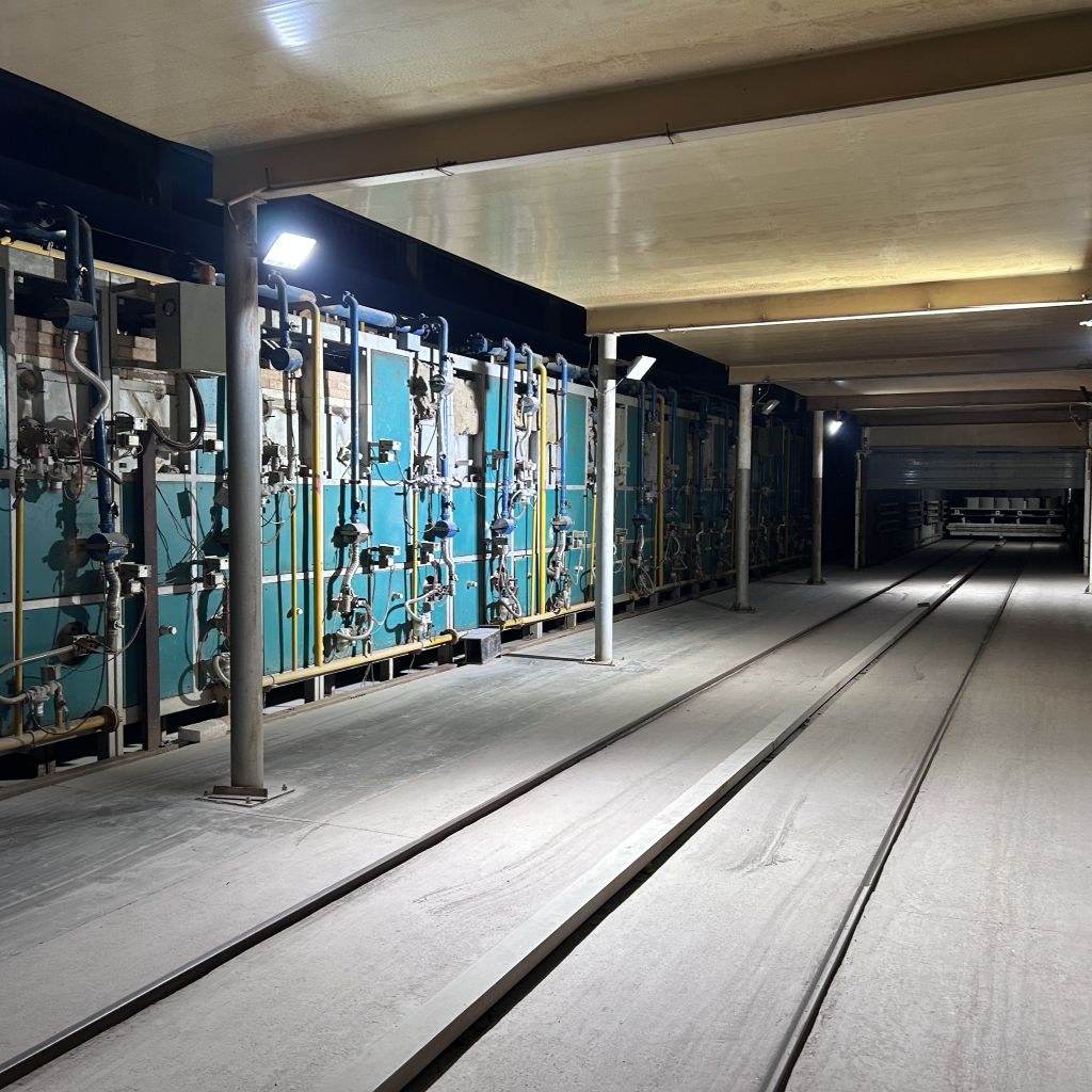 Exterior side of the 96-metre tunnel kiln at the TAITAO plant, showing burner piping and kiln-car rails