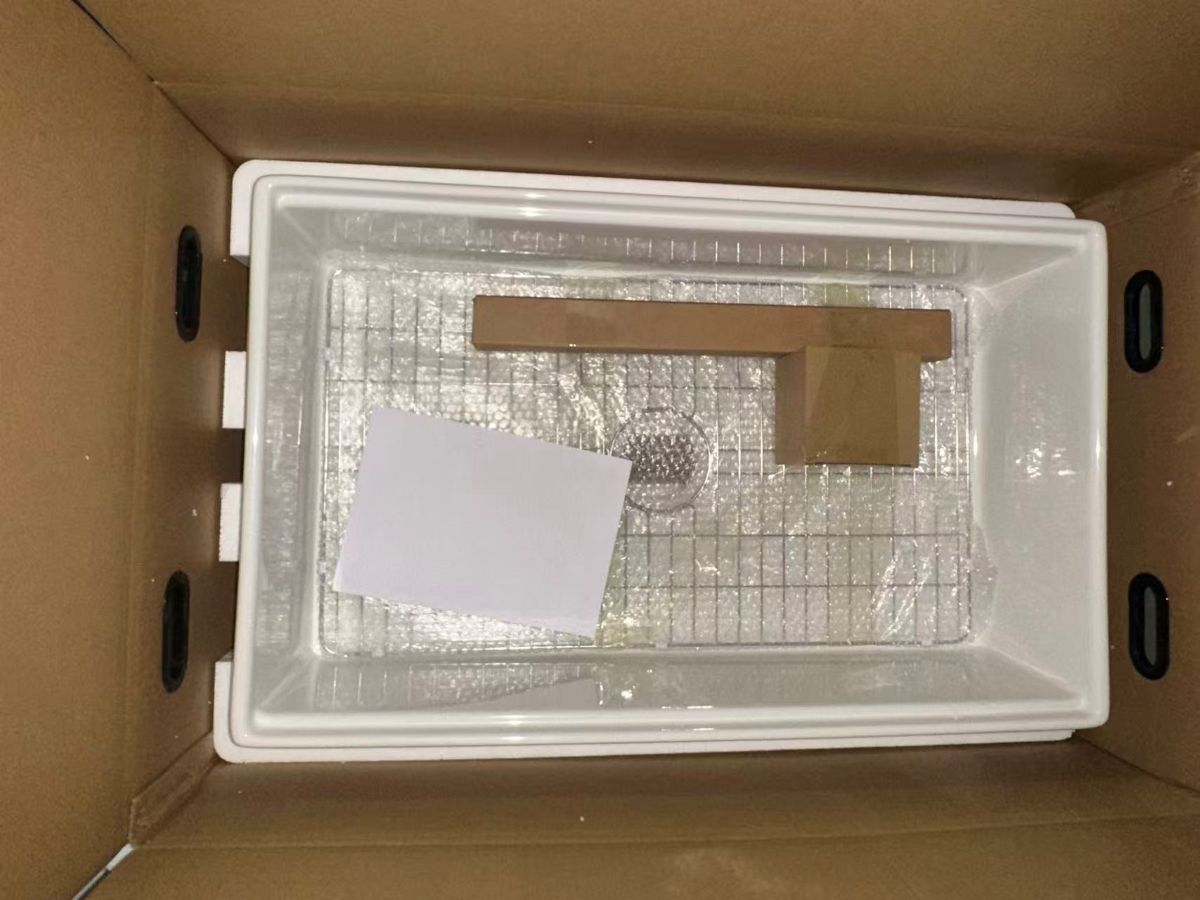 Interior of an export carton with the fireclay sink held on moulded cushioning blocks, seen from above