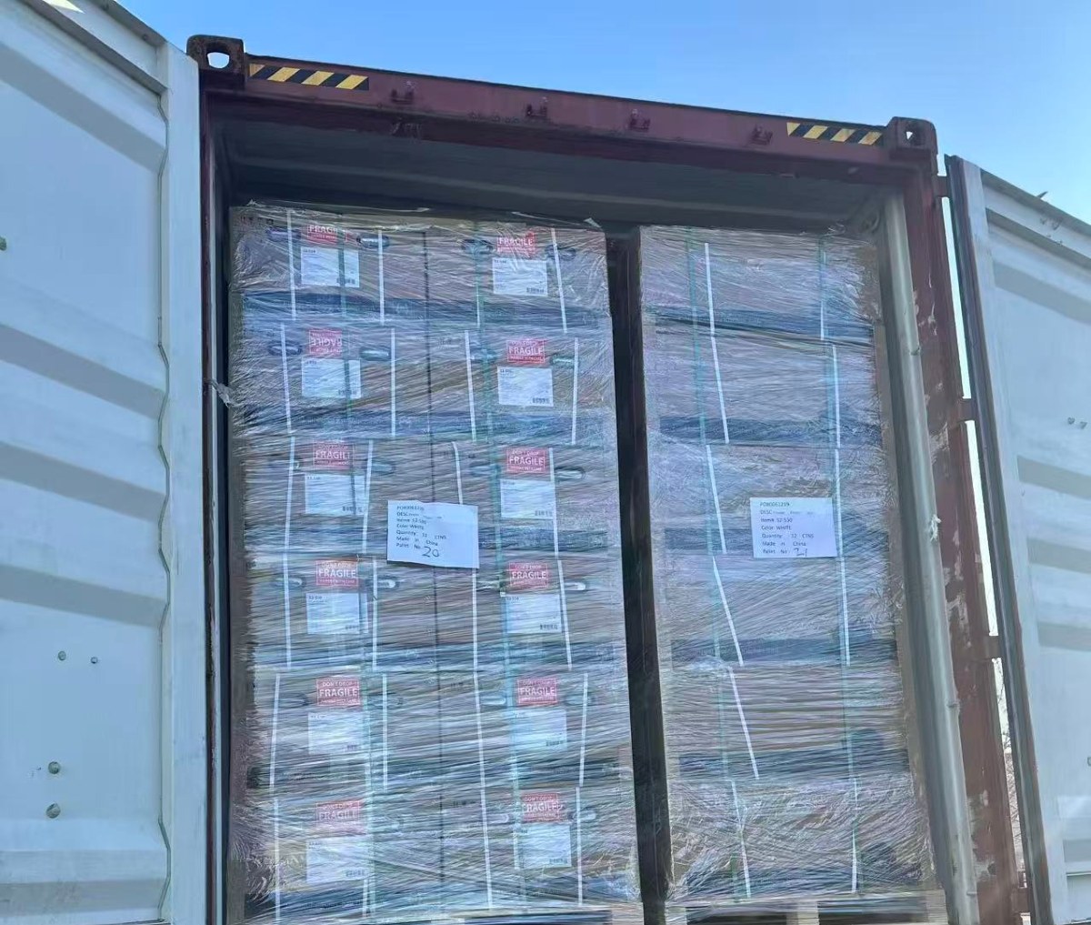 Stretch-wrapped cartons on pallets being loaded into a shipping container at the TAITAO works
