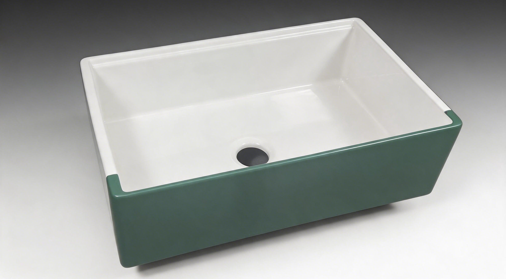 Dual-color fireclay farmhouse sink with a glossy white glazed bowl and a matte green apron front panel standing proud of the cabinet doors, cast in one body at the TAITAO line